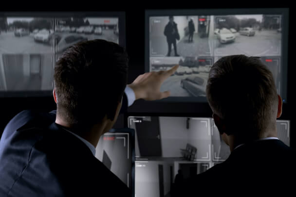 low-profile-corporate-campus Two security personnel reviewing video security camera screens.