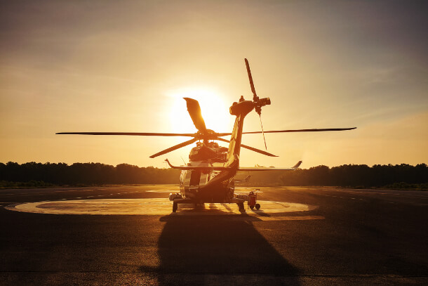 Helicopter on a landing pad with a sunset.