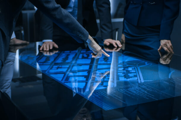 Men in suits pointing to a map on a table.