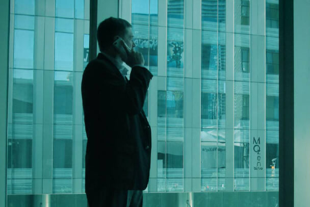 Executive on the phone looking out of high rise window.