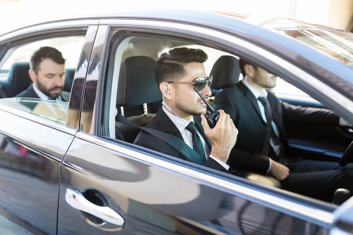 Two security drivers with executive in backseat